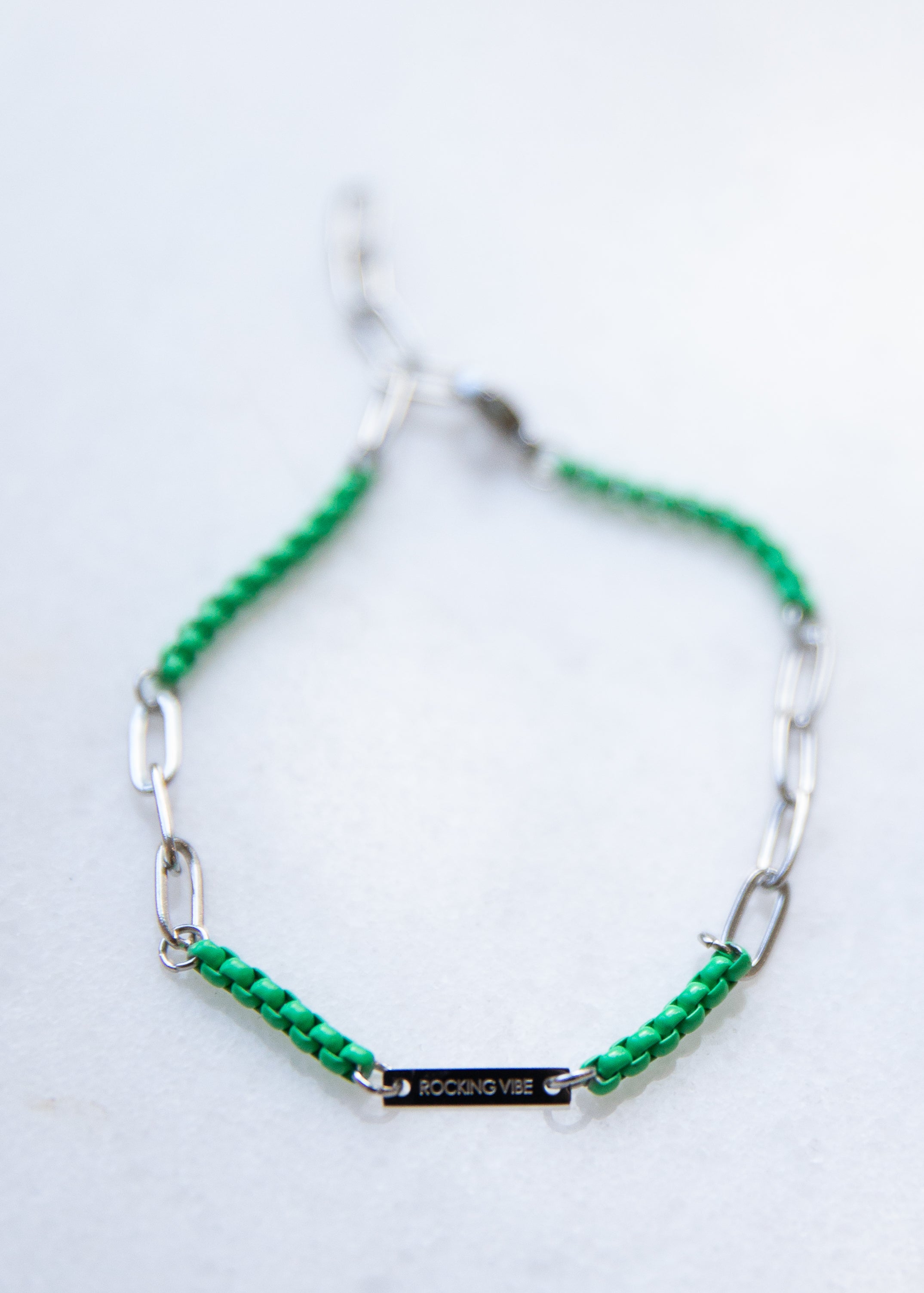 Green beaded bracelet with silver chain on a white background