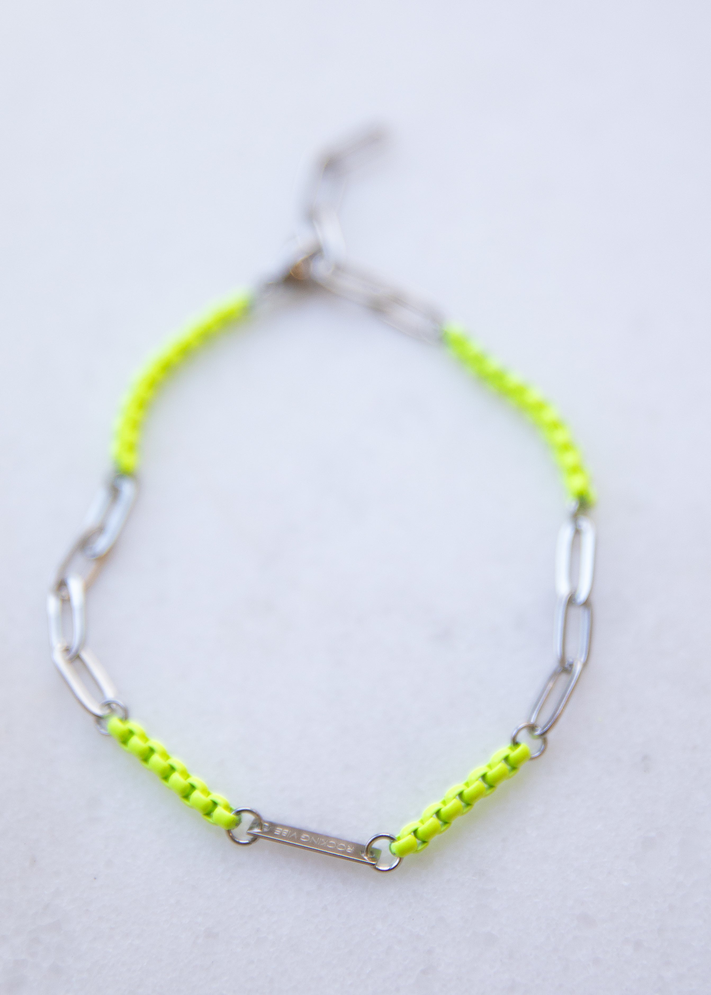 Neon yellow bracelet with silver chain on a light gray background
